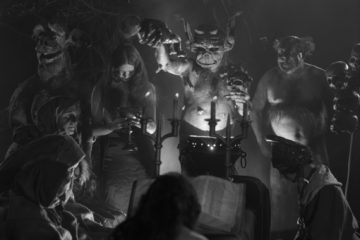 image en noir et blanc tirée du film Häxan : un rassemblement de socrières et démons éclairés par la lumière d'une bougie