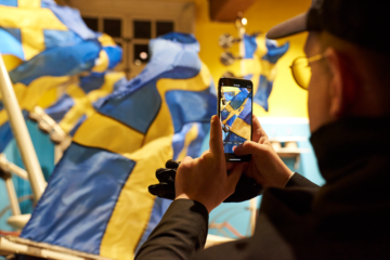 de dos un homme rpend en photo avec son smartphone des drapeaux suédois