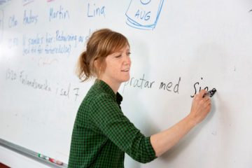 Woman writing on whiteboard.