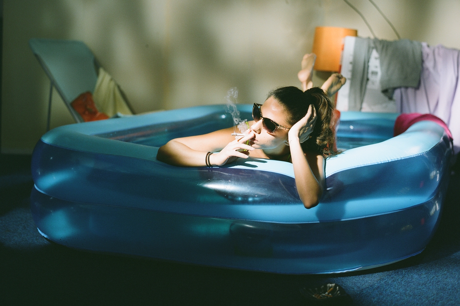 A girl smokes in an inflatable swiming pool