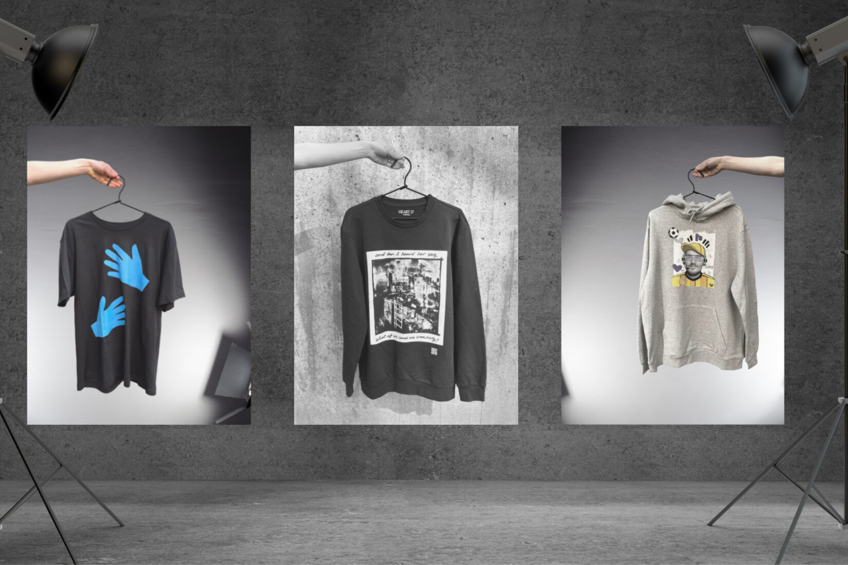 Photo of two sweat shirts and a t-shirt bearing printed illustrations and shown in the spotlight.
