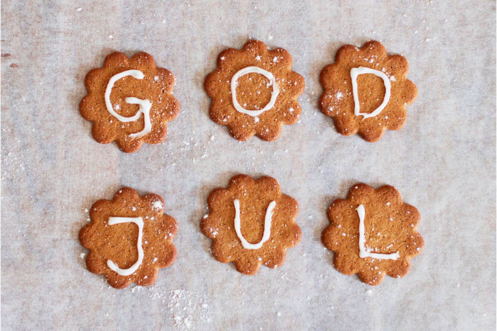6 "pepparkakor" sur lesquels sont écrits au sucre glace les lettres qui forment "God Jul", "Joyeux Noël".