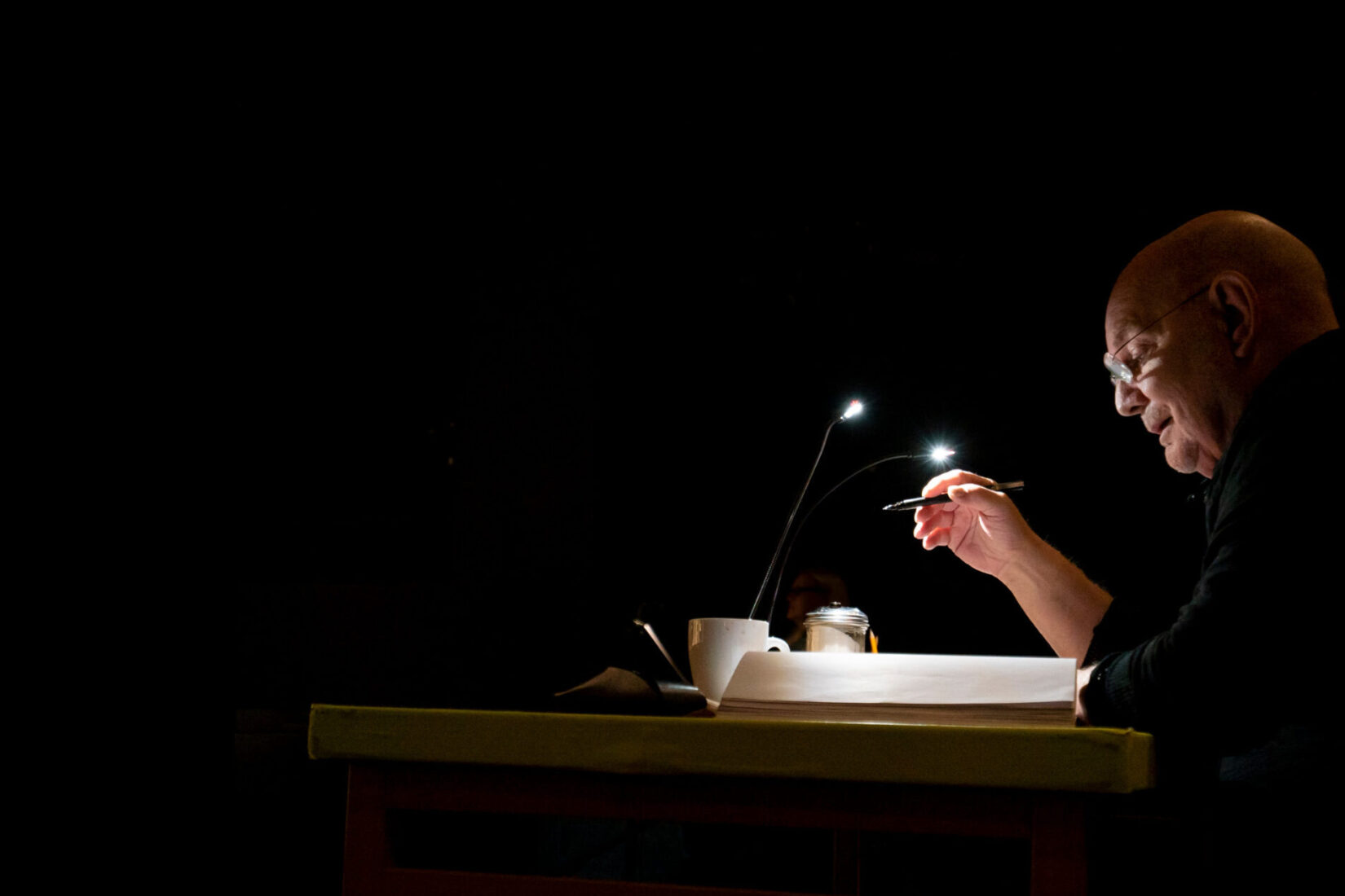 Photo of Lars Norén writing at his desk in the dark.