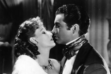 Photo en noir et blanc de Greta Garbo et son partenaire dans le film Le Roman de Marguerite, dans une posture amoureuse et sensuelle.