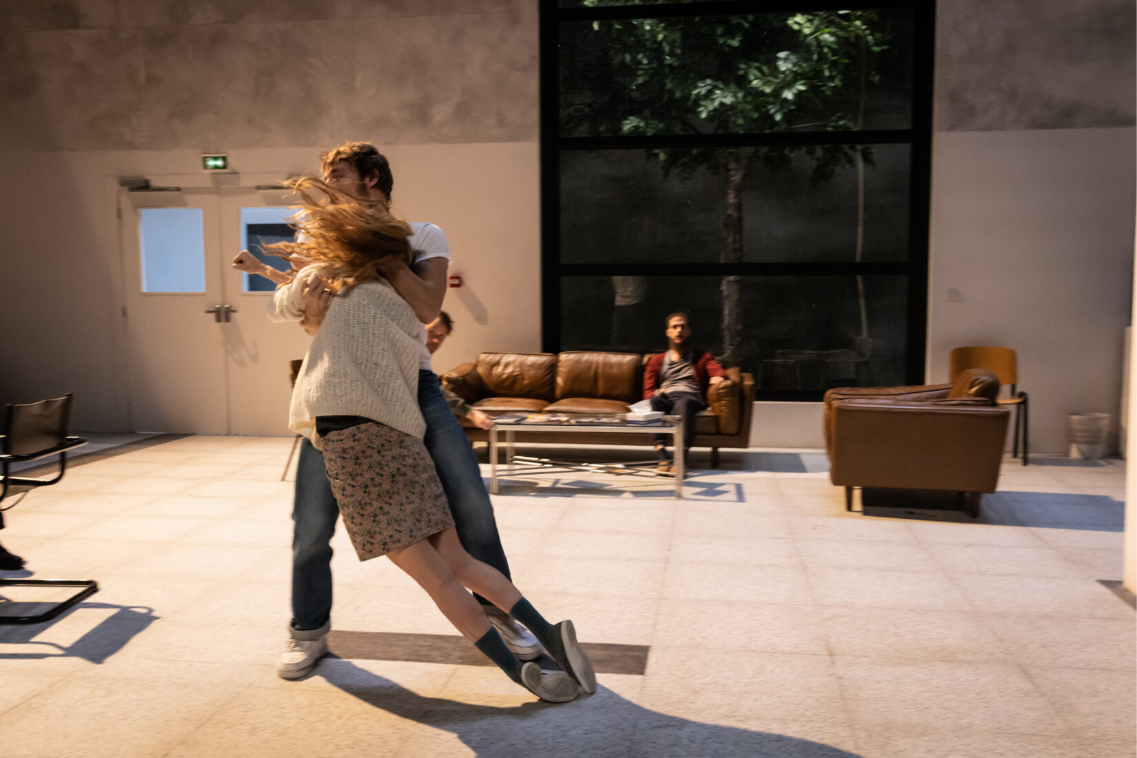 Photo d'une scène de la pièce "Kliniken" mise en scène par Julie Duclos aux Gémeaux, montrant un homme rattrapant une femme en train de tomber.