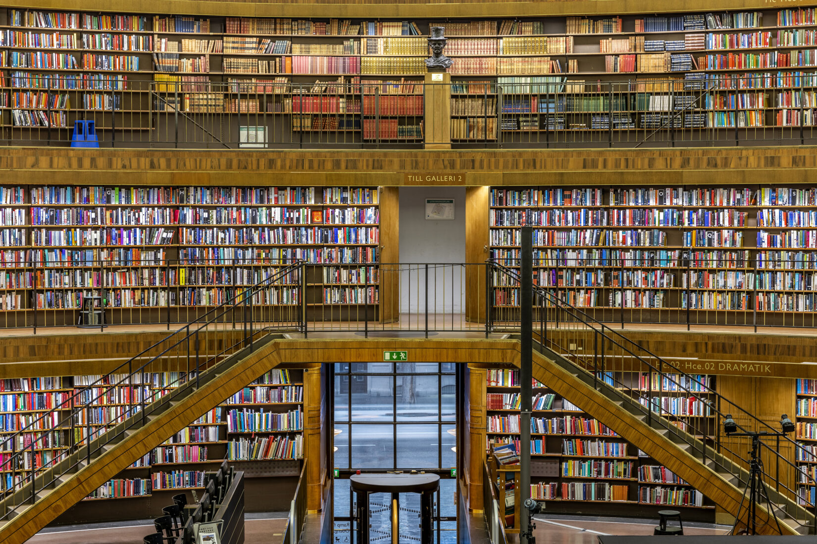 Photo d'une bibliothèque à plusieurs étages avec le longs rayonnages de livres à chacun d'eux.
