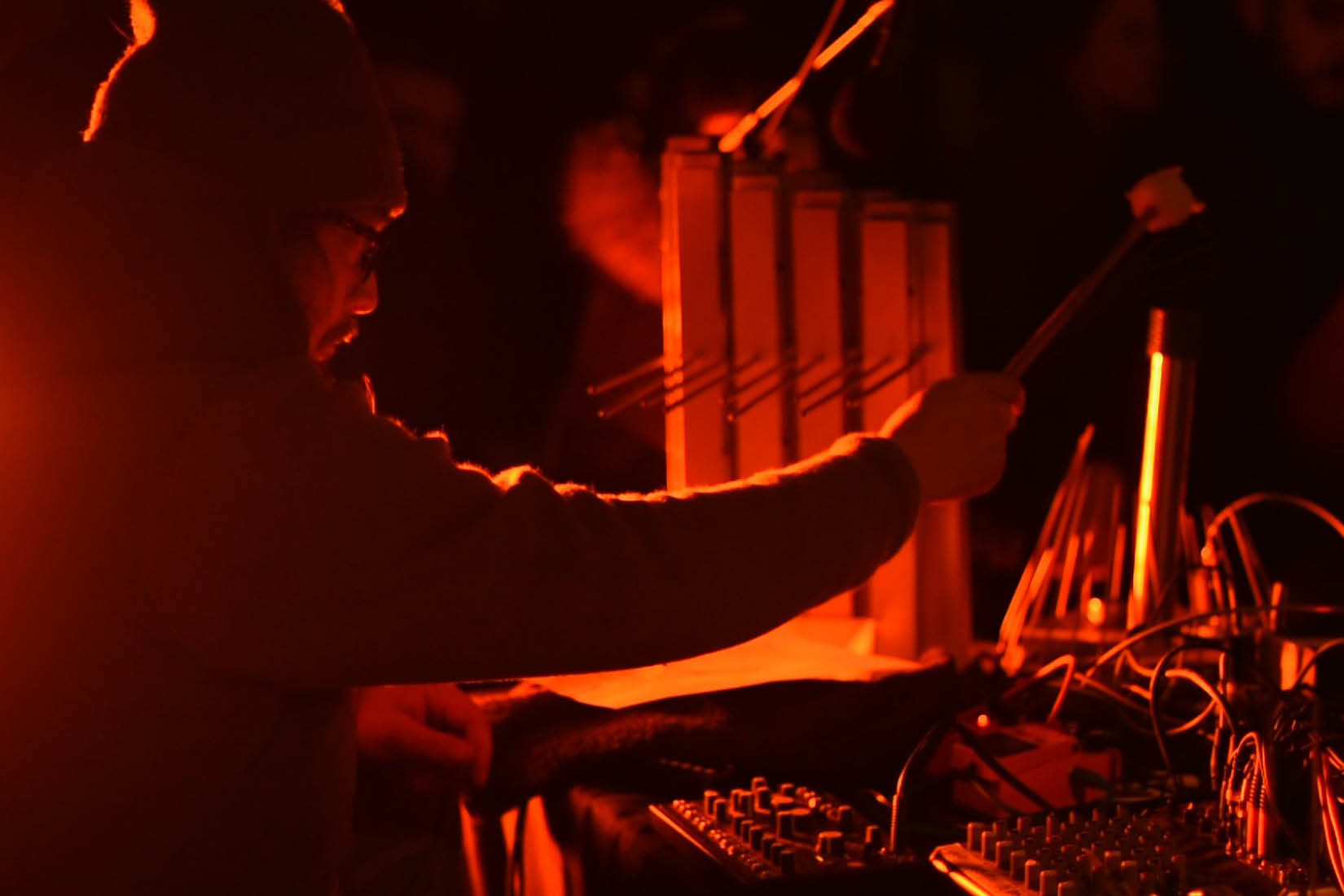 Dans l'obscurité, silhouette d'un musicien jouant d'un instrument électronique.