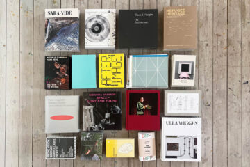 Selection of art books laid on a wooden floor in a rectangle.