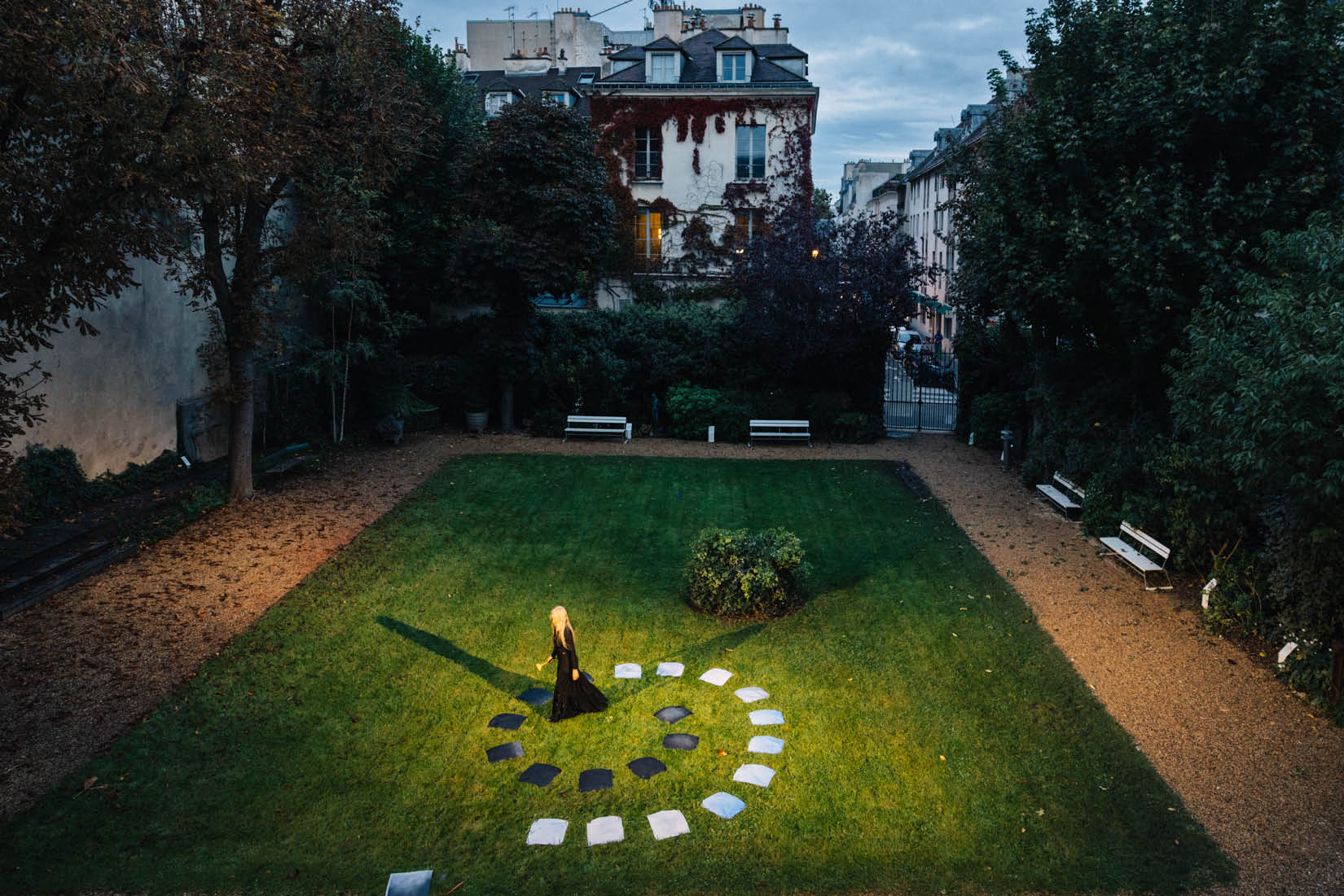 Photo de l'artiste se tenant au milieu de ses oeuvres disposées en spirale dans le jardin de l'Institut suédois, à l'aube.