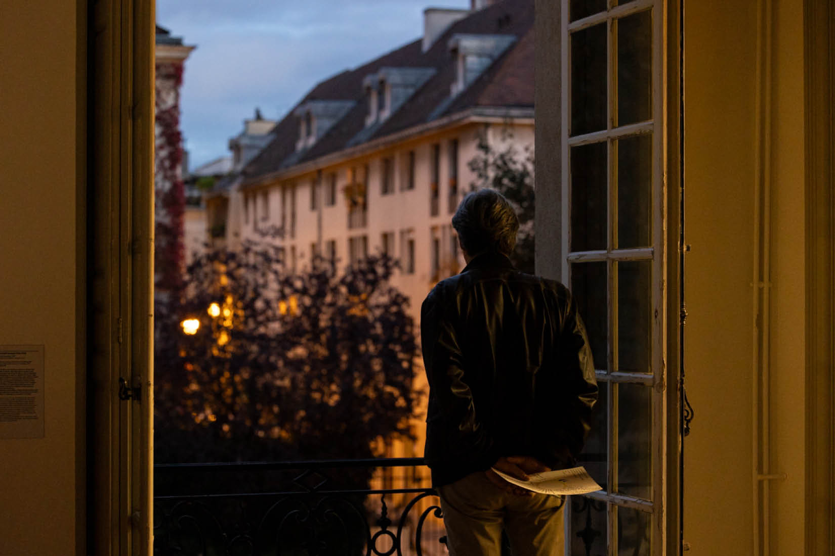 Photo d'une personne de dos, contemplant le ciel nocturne de Paris depuis une fenêtre ouverte d'une salle de l'Institut suédois.