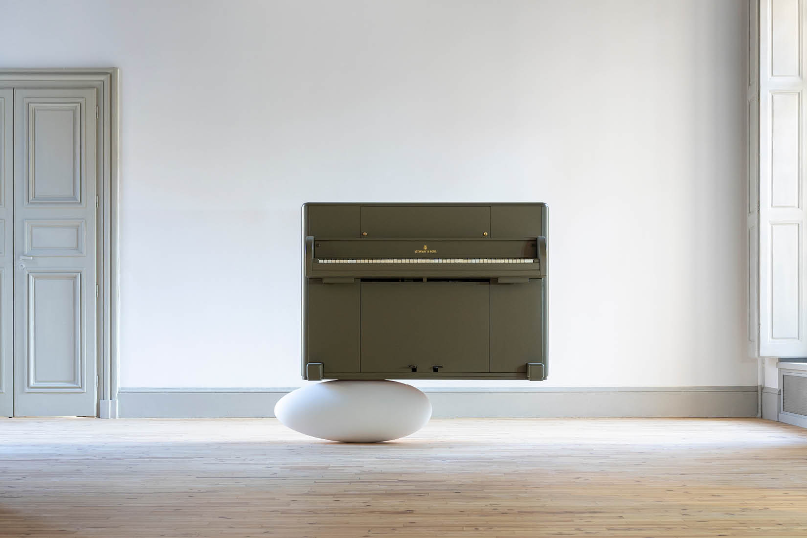 A piano standing on what looks like a white cocoon laid on the floor.