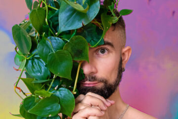 Visage du chanteur à demi caché par un lierre tombant, sur fonds rose et violet.