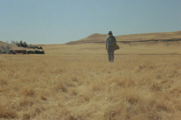 A lonely man walking on a field.