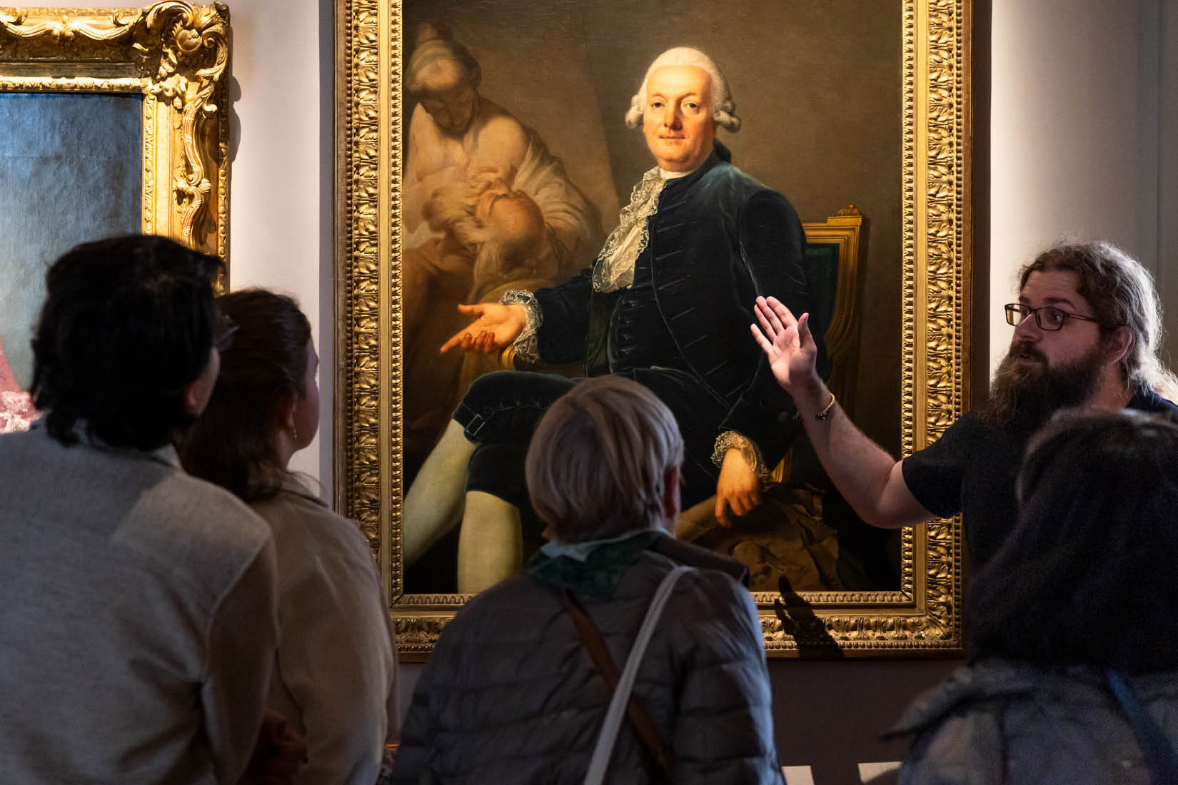 Guide montrant des détails d'un tableau à un groupe de visiteur.ses.