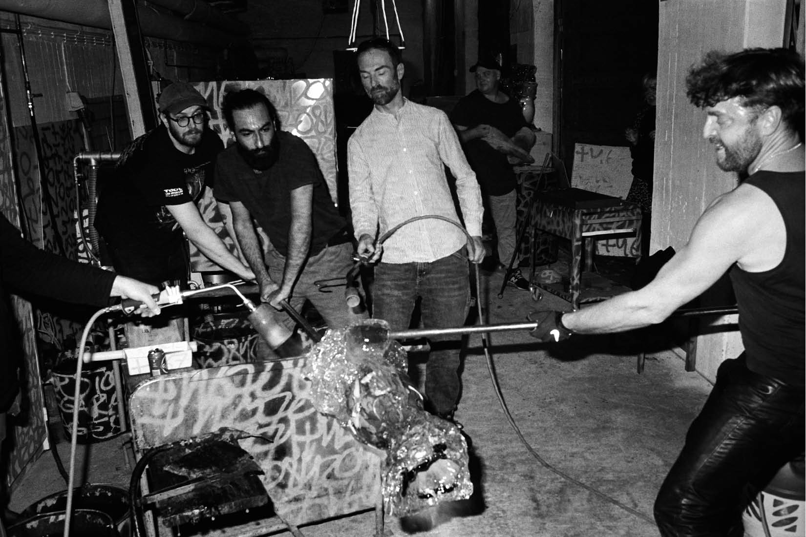 A man holding a stick into a fire oven to make a glass sculpture.