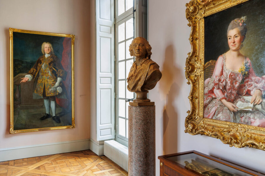 Vue d'une salle d'exposition, avec tableaux et sculpture.