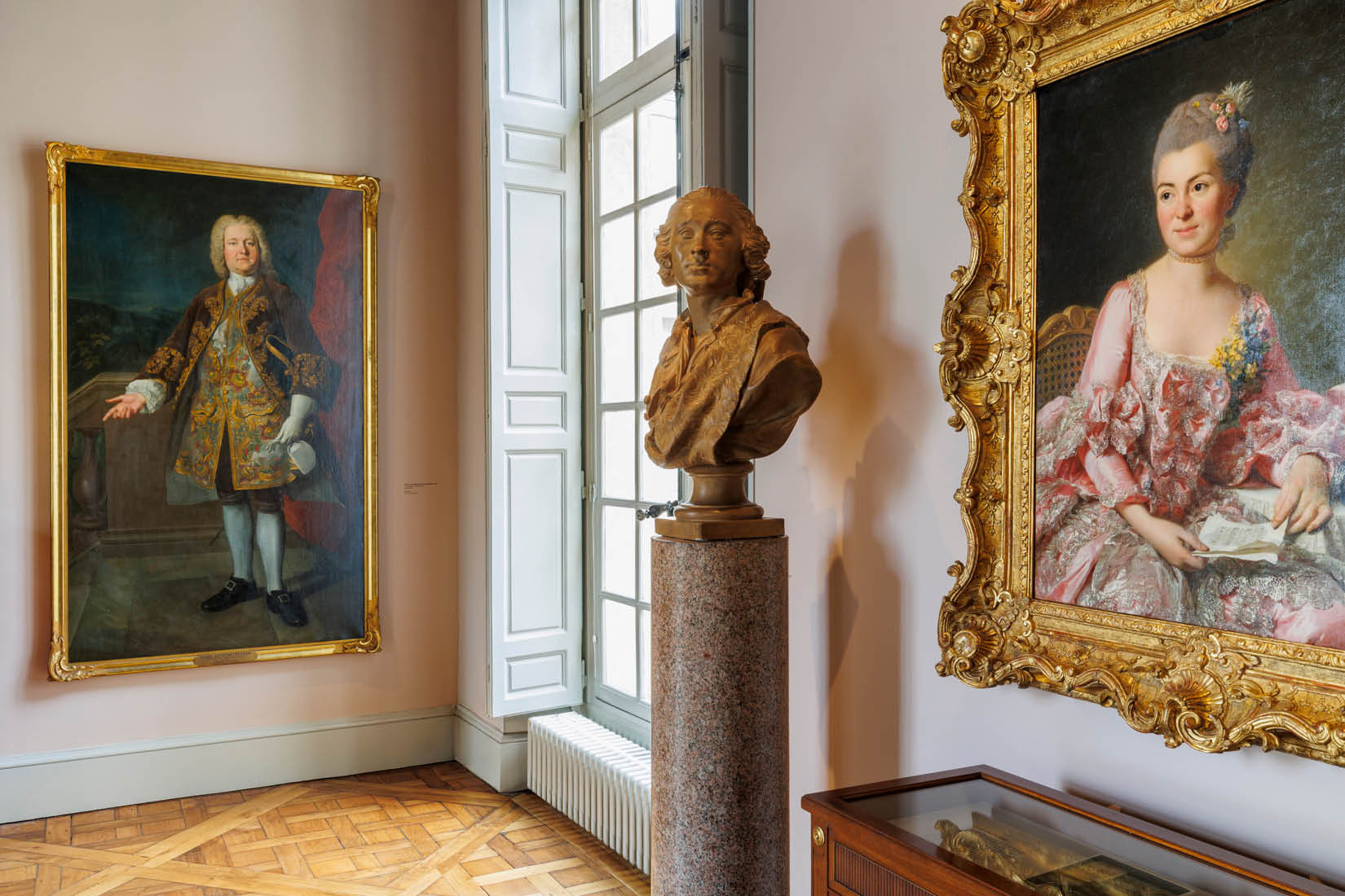 Vue d'une salle d'exposition, avec tableaux et sculpture.