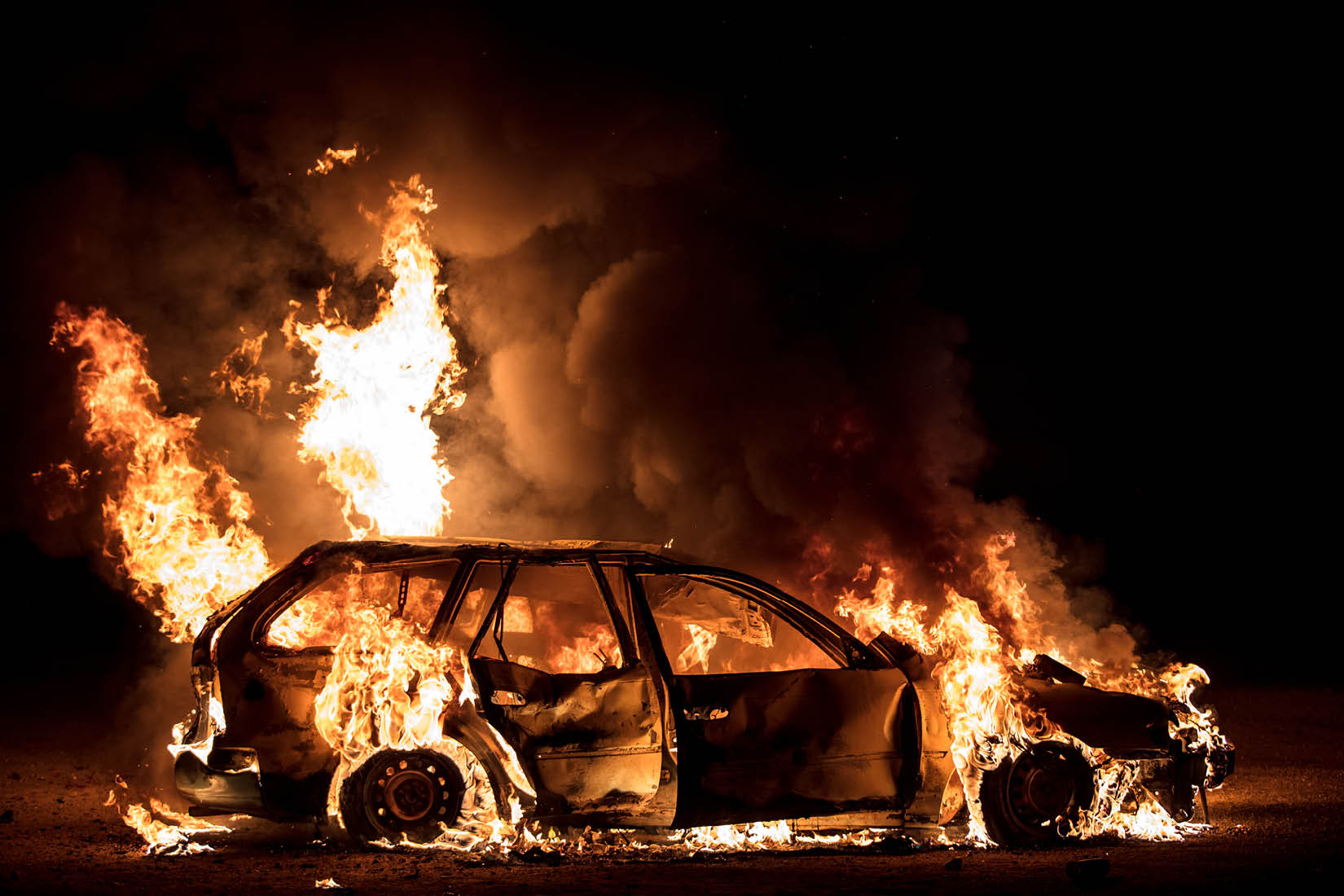 Une voiture en feu dans la nuit.