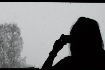 Silhouette of a person standing in front of a snowy landscape, taking a picture.