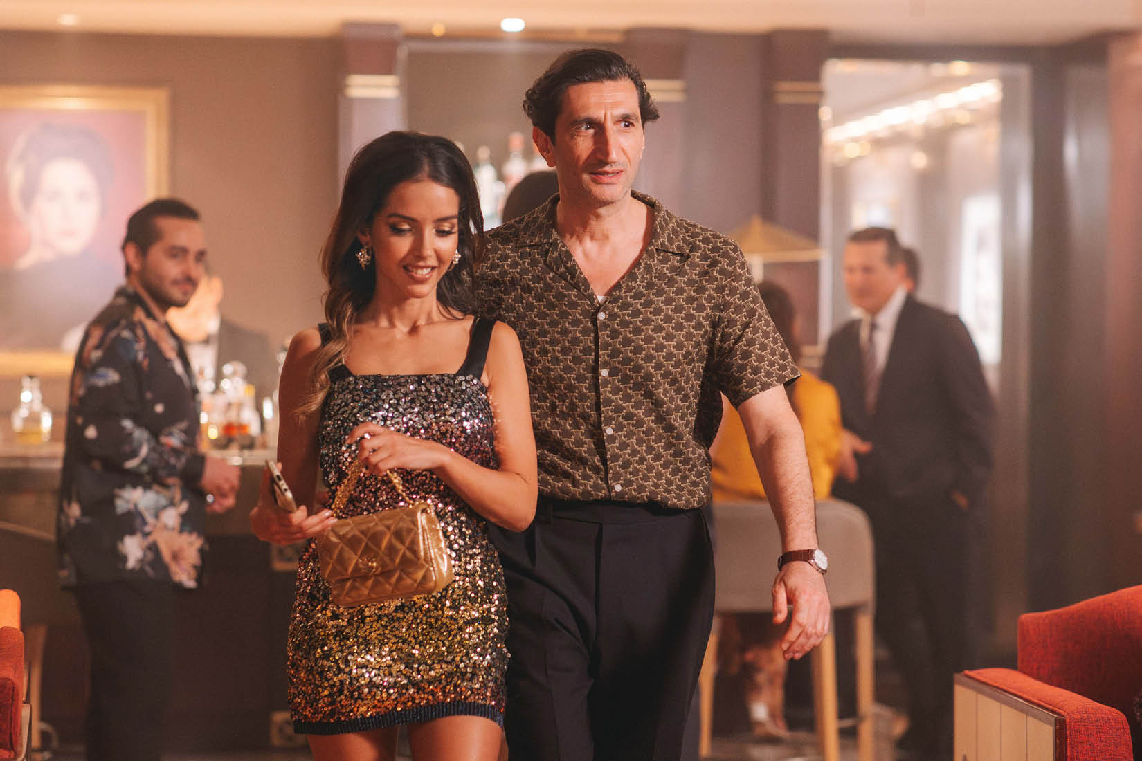 Un homme et une femme s'avancent côte-à-côte dans ce qui ressemble à un bar chic.